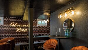 A room with patterned wallpaper, a pool table, a bar area with stools, and a neon sign reading "Home on Range". - The Wild Western: 5 BR, Hot Tub, Sauna, 2 Game Rooms, Putting Green, & more! (Denver)
