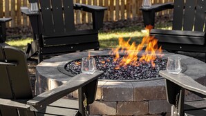 A fire pit with two glasses on metal stands, surrounded by black Adirondack chairs. - The Wild Western: 5 BR, Hot Tub, Sauna, 2 Game Rooms, Putting Green, & more! (Denver)