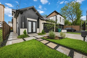 Ein modernes, zweistöckiges Haus mit Garage, gepflegtem Rasen und befestigter Auffahrt.
