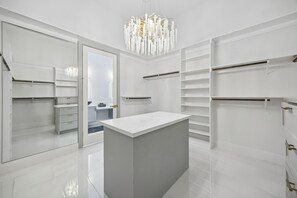 Ein modernes, weißes Interieur mit einer zentralen Kochinsel, Einbauschränken und einem Kronleuchter.