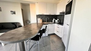 A modern kitchen with white cabinets, a grey countertop, and a built-in microwave. - Apartment in Grau-du-roi With Sea View (Le Grau-Du-Roi)