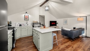 Una cocina moderna con armarios blancos, una isla central y un comedor con sofá.