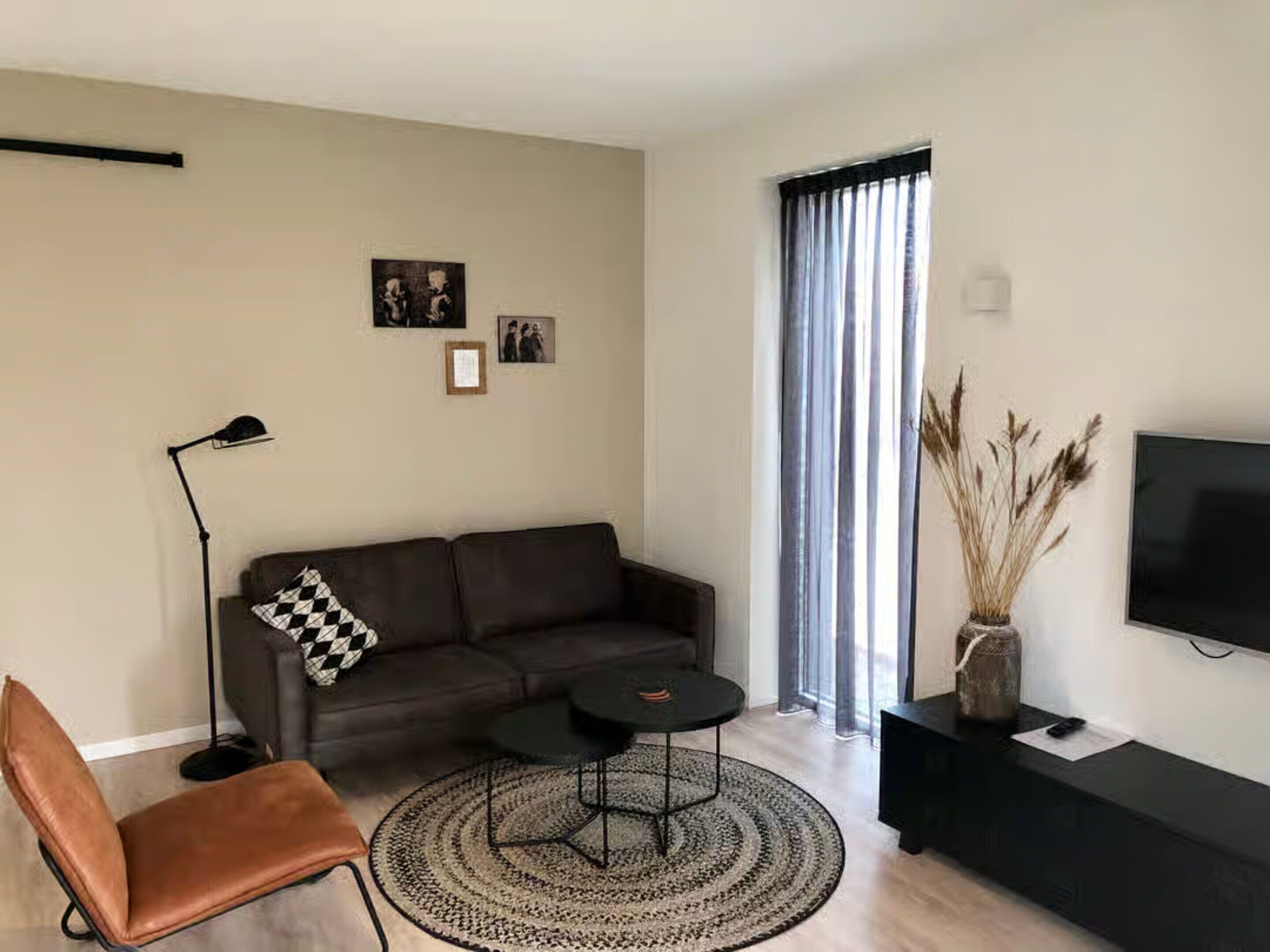 A modern living room with a sofa, a coffee table, a chair, a floor lamp, and a TV on a stand.
