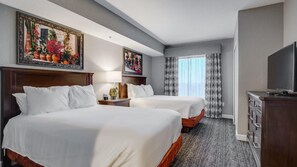 Een hotelkamer met twee bedden, een televisie, een bureau en een dressoir.
