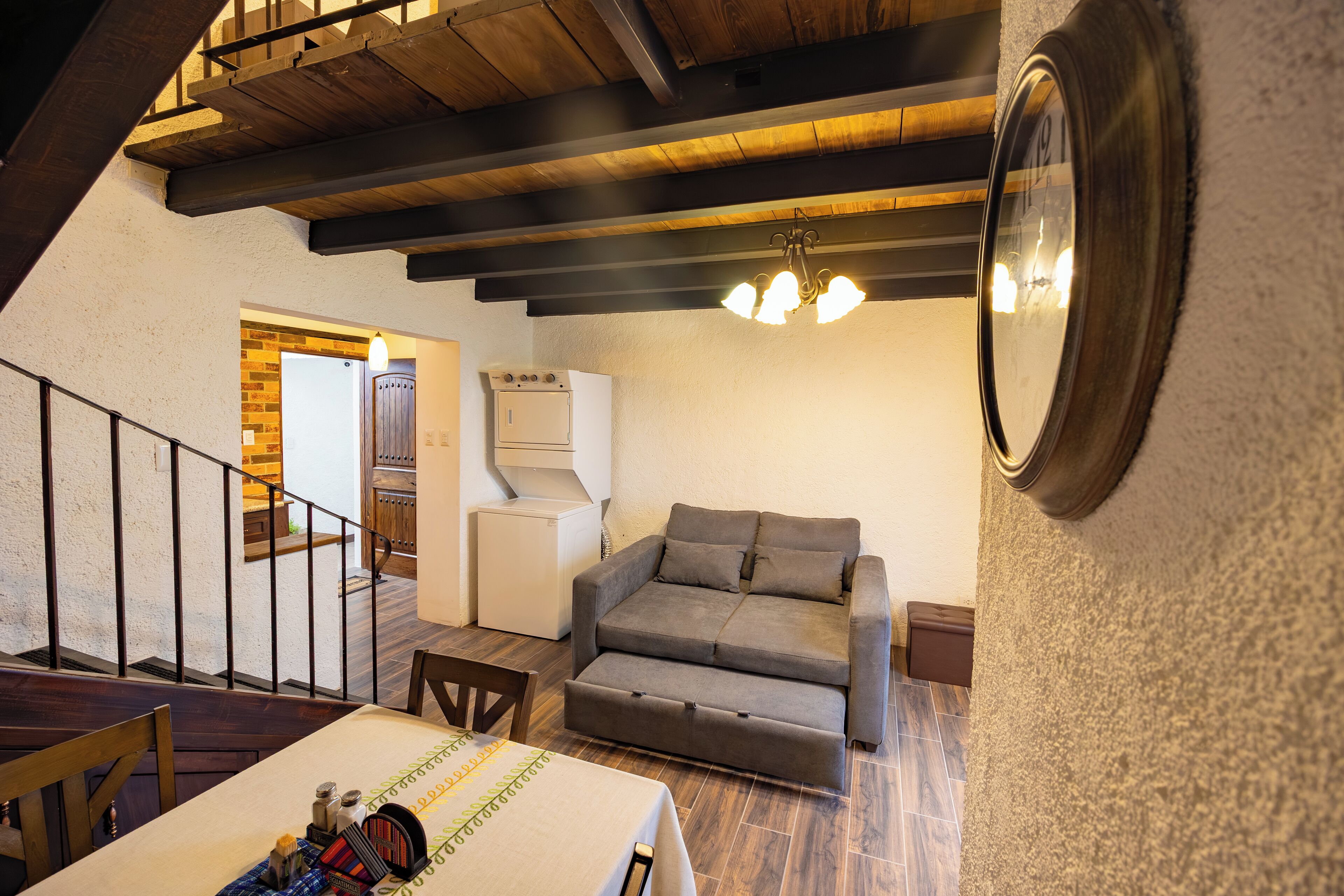 A cozy living area with a sofa, a dining table, and a kitchen in the background.