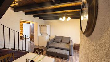A cozy living area with a sofa, a dining table, and a kitchen in the background.
