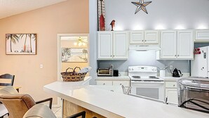 A modern kitchen with white cabinets, a central island, and a star decoration on the wall. - NEAR Fleming island LUXE-POOL-FIRE pit-games-more (Middleburg)