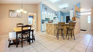 A modern kitchen with white cabinets, a central island, and bar stools. - NEAR Fleming island LUXE-POOL-FIRE pit-games-more (Middleburg)