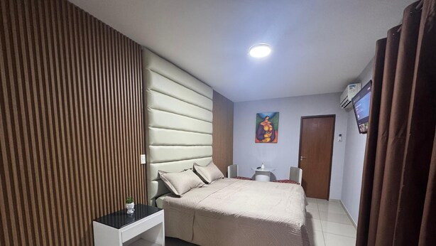 A modern bedroom with a large bed, a small bedside table, a decorative rug, and a painting on the wall. - Exclusive Condominium Home - Resort Style Living with Pool and Parks 🌴🏊‍♂️ (Santa Cruz de la Sierra)