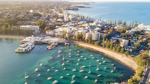 Luftaufnahme einer Küstenstadt mit einer Marina, klarem türkisblauem Wasser und einer Mischung aus Wohn- und Geschäftshäusern.