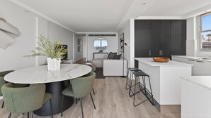 Una cocina moderna con armarios oscuros, encimera blanca y una mesa redonda de comedor con sillas verdes.