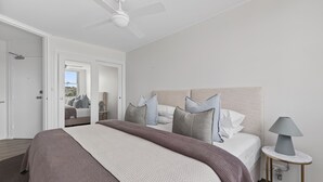 Un dormitorio moderno con una cama grande, un ventilador de techo y una mesita de noche con lámpara.