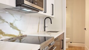 Una cocina moderna con estufa, horno e grifo negro.