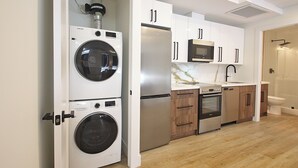 Una cocina moderna con un refrigerador de acero inoxidable, un microondas y una lavadora.