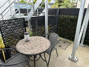 Un'area patio con un tavolo rotondo e due sedie, un lanterne decorativo e una scala in metallo.