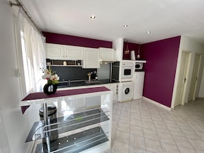 A compact kitchen with white cabinets, a built-in oven, a microwave, and a washing machine. - L'Ensoleillé - ROQUEFORT DES CORBIERES (ROQUEFORT DES CORBIERES)