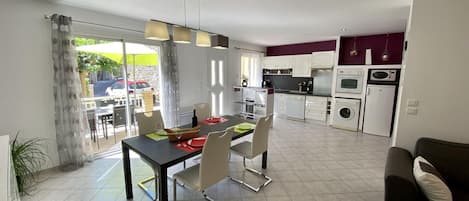 A modern kitchen with white cabinets, a dining area with a table and chairs, and a view of the outside.