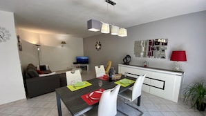 En moderne opholdsstue med spiseplads, sofa, fjernsyn og et køkken.