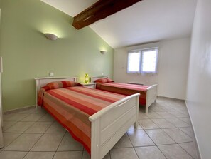 A room with two beds, a window, and a ceiling with exposed beams. - L'Ensoleillé - ROQUEFORT DES CORBIERES (ROQUEFORT DES CORBIERES)