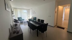 Un salon moderne avec un coin repas, de grandes fenêtres et une vue sur l’extérieur.