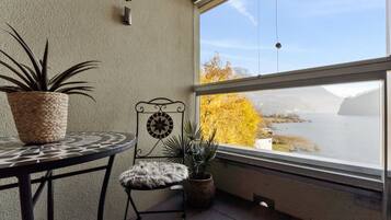 Ein Balkon mit Blick auf ein Gewässer, einer Topfpflanze, einem Stuhl und einem Tisch.
