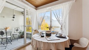 Un coin repas accueillant, avec une table dressée pour deux, une vue sur un lac et une montagne en arrière-plan.