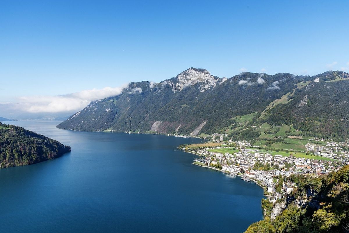 Ein weiter Blick auf einen See, umgeben von Bergen und einer Stadt.
