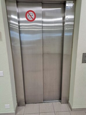 An elevator with a no-smoking sign, a button panel, and a wall-mounted light switch.