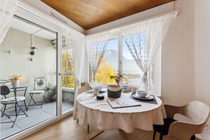 A dining area with a round table, chairs, and a view of a mountainous landscape through large windows.