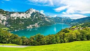 Un paysage montagneux avec un lac, des champs verdoyants et un petit village.
