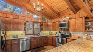 A wooden cabin kitchen with granite countertops, a dishwasher, a stove, and a sign that says "let's eat". - The Woodhaven Cabin In Massanutten (McGaheysville)