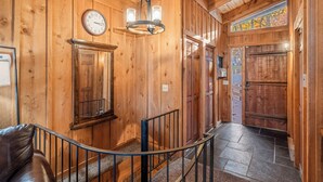 A wooden interior with a clock, a chandelier, and a staircase leading to another room. - The Woodhaven Cabin In Massanutten (McGaheysville)