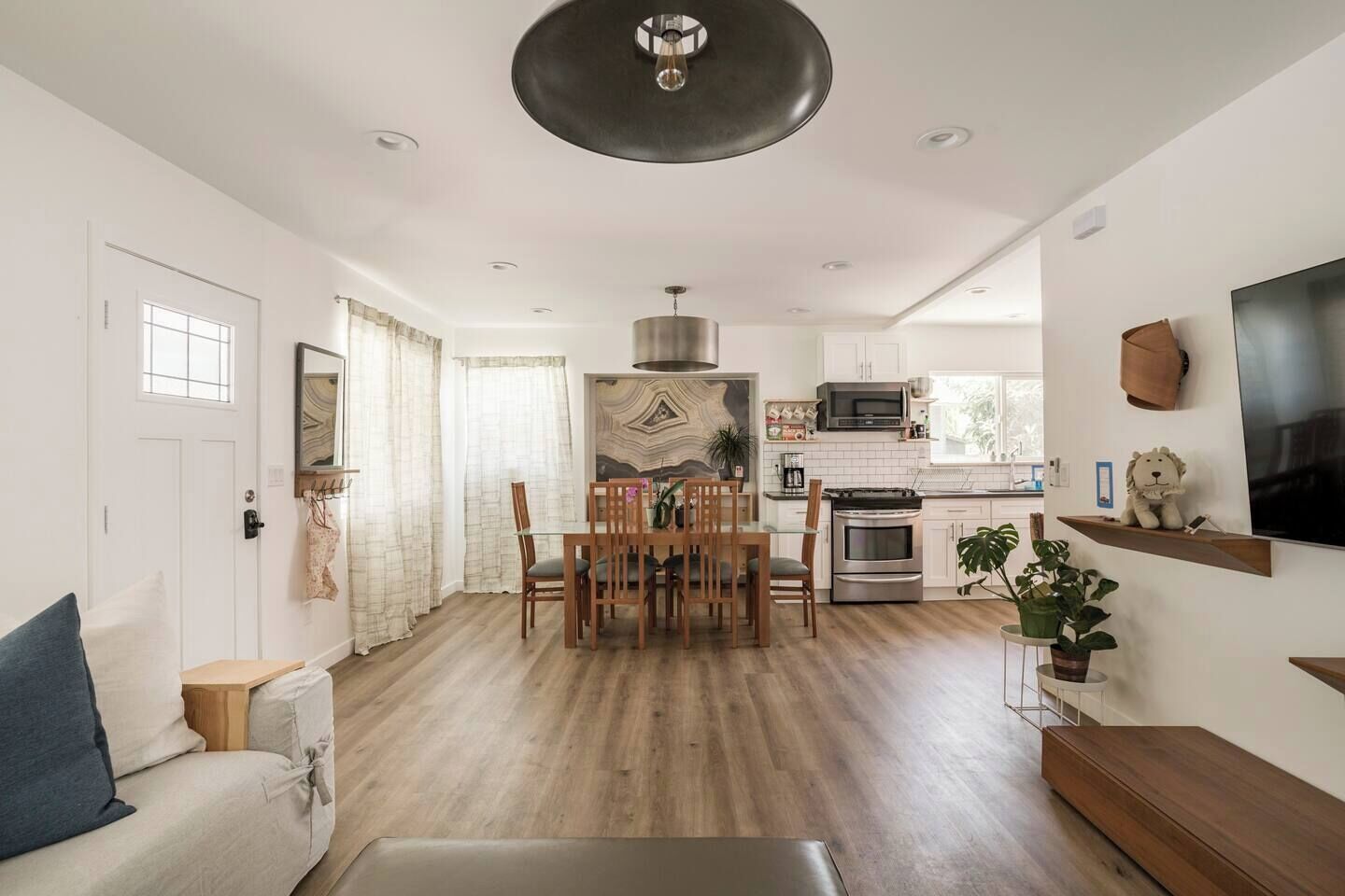 A modern kitchen with a dining area, a sofa, and a TV.