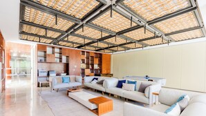 A spacious living area with a high ceiling, built-in wooden shelving, and a large window providing natural light. - 2BR Family Haven in Secure Resort Community with Beach Club Access (Isla Mujeres)