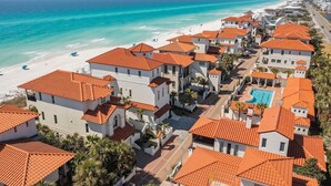 Un quartier résidentiel en bord de mer, avec des bâtiments aux toits de tuiles rouges, une plage et une piscine.