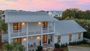 A two-story house with a balcony, a front porch with chairs, and a well-maintained lawn. - Pearl Sands - Private Pool and Golf Cart! (Destin)