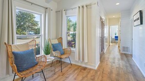 A hallway with wicker chairs, a small table, and a potted plant. - Pearl Sands - Private Pool and Golf Cart! (Destin)