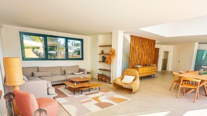 A modern living room with a sofa, coffee table, and a dining area with a wooden table and chairs. - Villa Alimea Di San Ciprianu (sainte lucie de porto vecchio)