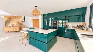 Una cocina moderna con armarios color turquesa, una encimera blanca y una lámpara colgante.