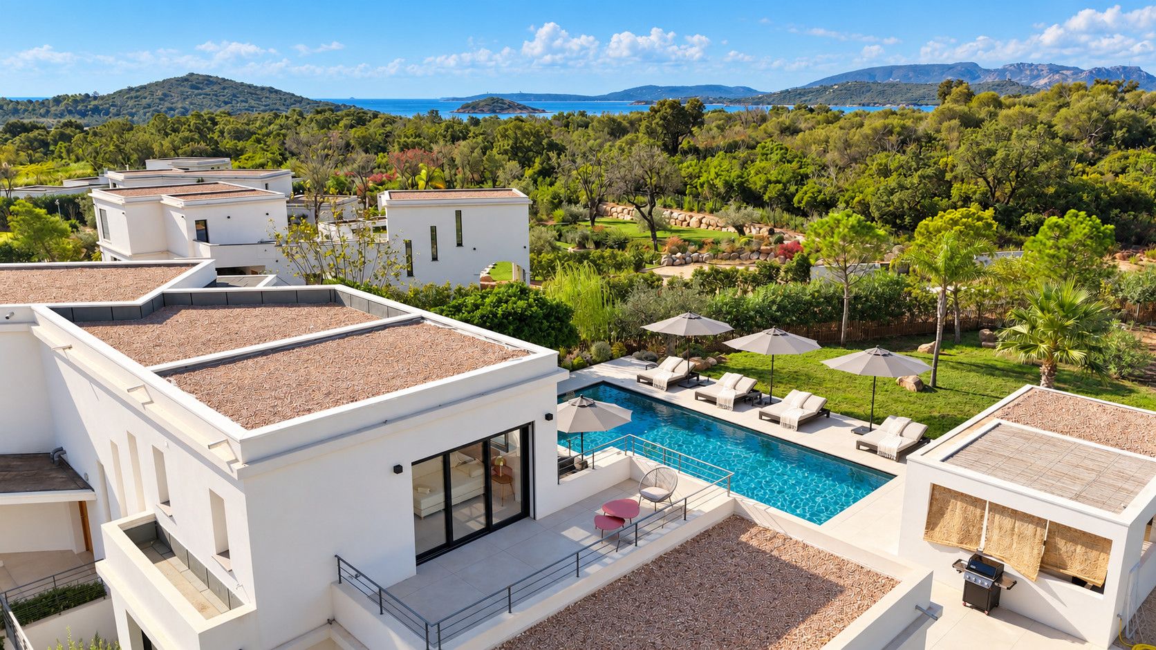 A modern villa with a rooftop pool, surrounded by lush greenery and a mountainous backdrop.