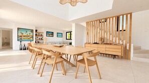 A spacious dining area with a long wooden table and chairs, a wooden cabinet with drawers, and a staircase with a wooden railing. - Villa Alimea Di San Ciprianu (sainte lucie de porto vecchio)