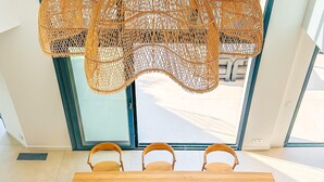 A wooden dining table with four chairs, two decorative salt shakers, and a woven hanging light fixture above. - Villa Alimea Di San Ciprianu (sainte lucie de porto vecchio)