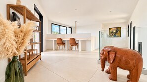 A modern interior with a dining area, a large wooden bookshelf, and a unique elephant sculpture. - Villa Alimea Di San Ciprianu (sainte lucie de porto vecchio)
