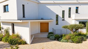 Una casa moderna de dos plantas con entrada pavimentada y puerta de madera.