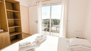 Een slaapkamer met een groot bed, een houten garderobe en een schuifdeur naar een buitenruimte.
