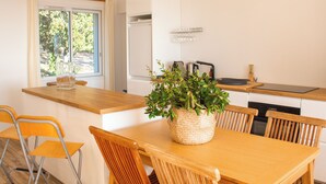 Een moderne keuken met een houten tafel en stoelen, een raam met gordijnen en een ingebouwde vaatwasser.