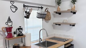 A modern kitchen with a wooden table, two chairs, a sink, and various kitchen items. - Bohemian and Romantic Cabin (Ocala)