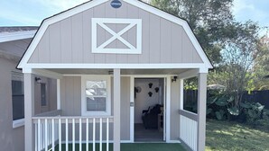 A small, single-story building with a gabled roof and a white-framed entrance. - Bohemian and Romantic Cabin (Ocala)