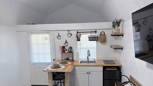 A compact kitchen with a wooden countertop, white cabinets, and a black dishwasher. - Bohemian and Romantic Cabin (Ocala)