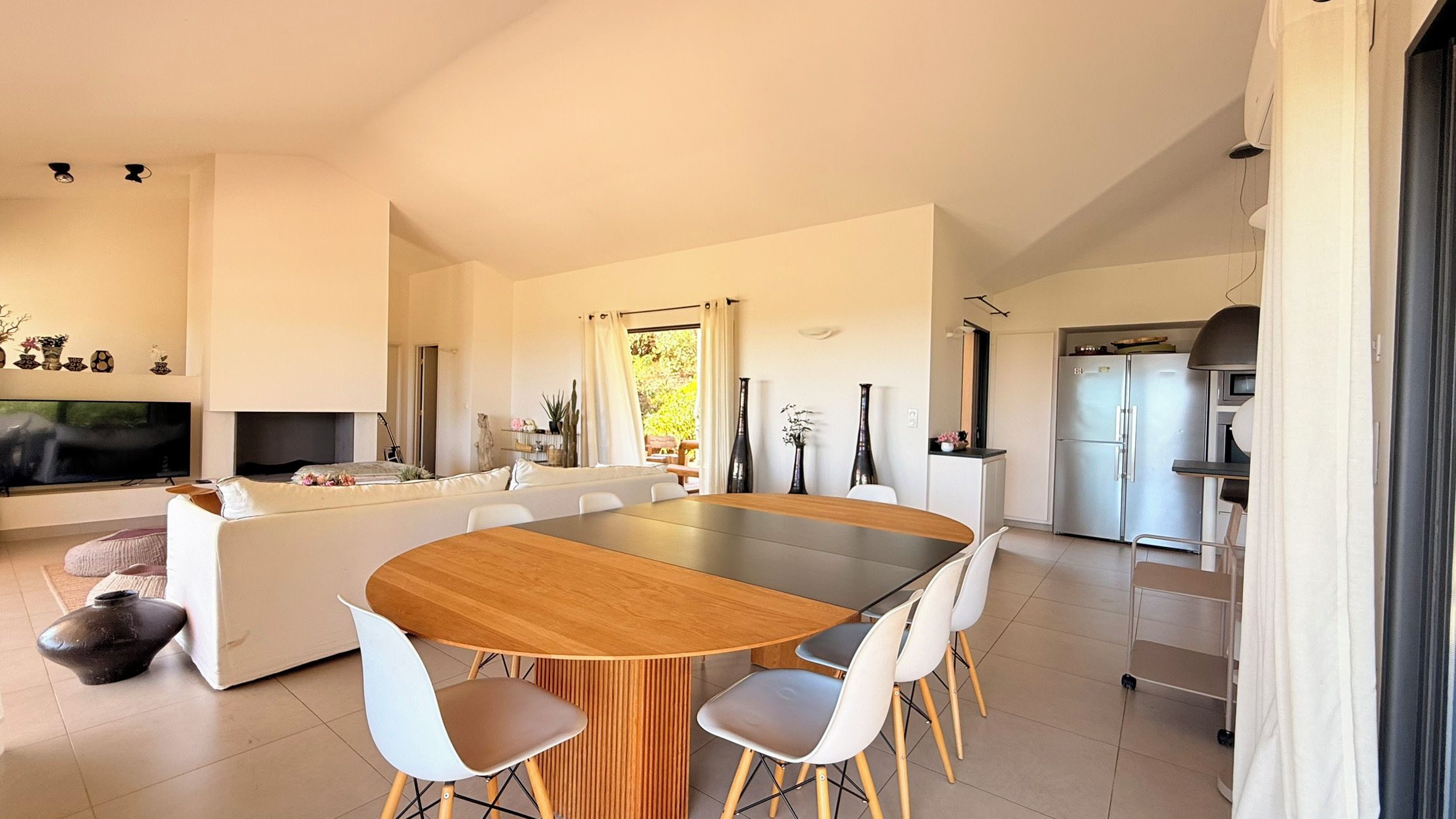 A modern living space with a dining area, kitchen, and a television.